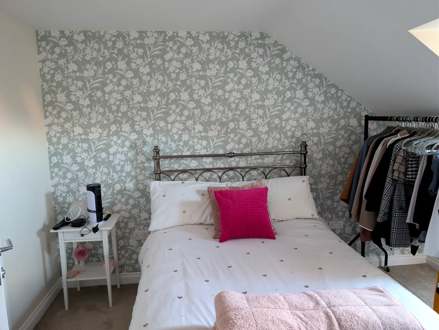 Bedroom with a pale botanical wallpaper feature wall beneath a sloping ceiling