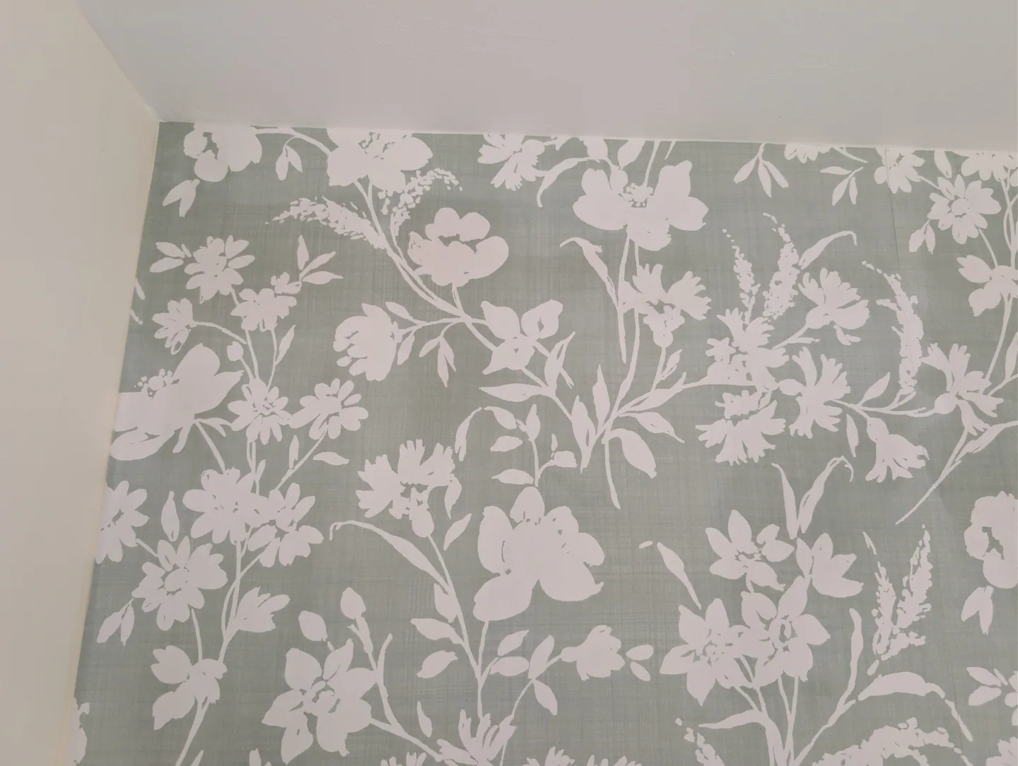 Close detail of pale leaves and flowers on grey botanical wallpaper