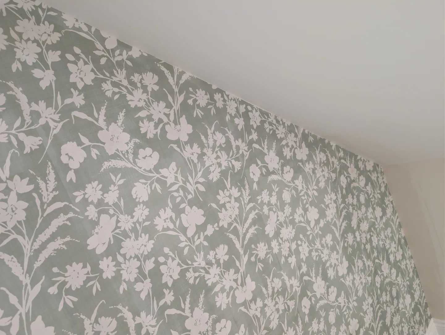 Botanical wallpaper neatly following the sloping bedroom ceiling