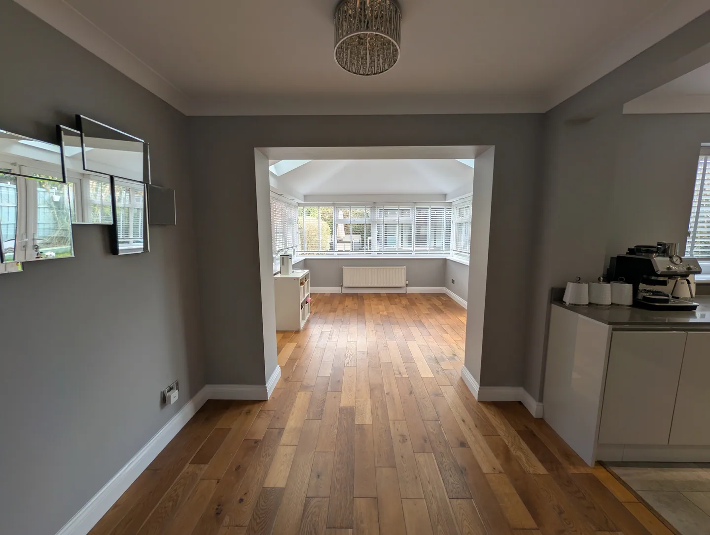 Grey-painted room opening into a bright sunroom