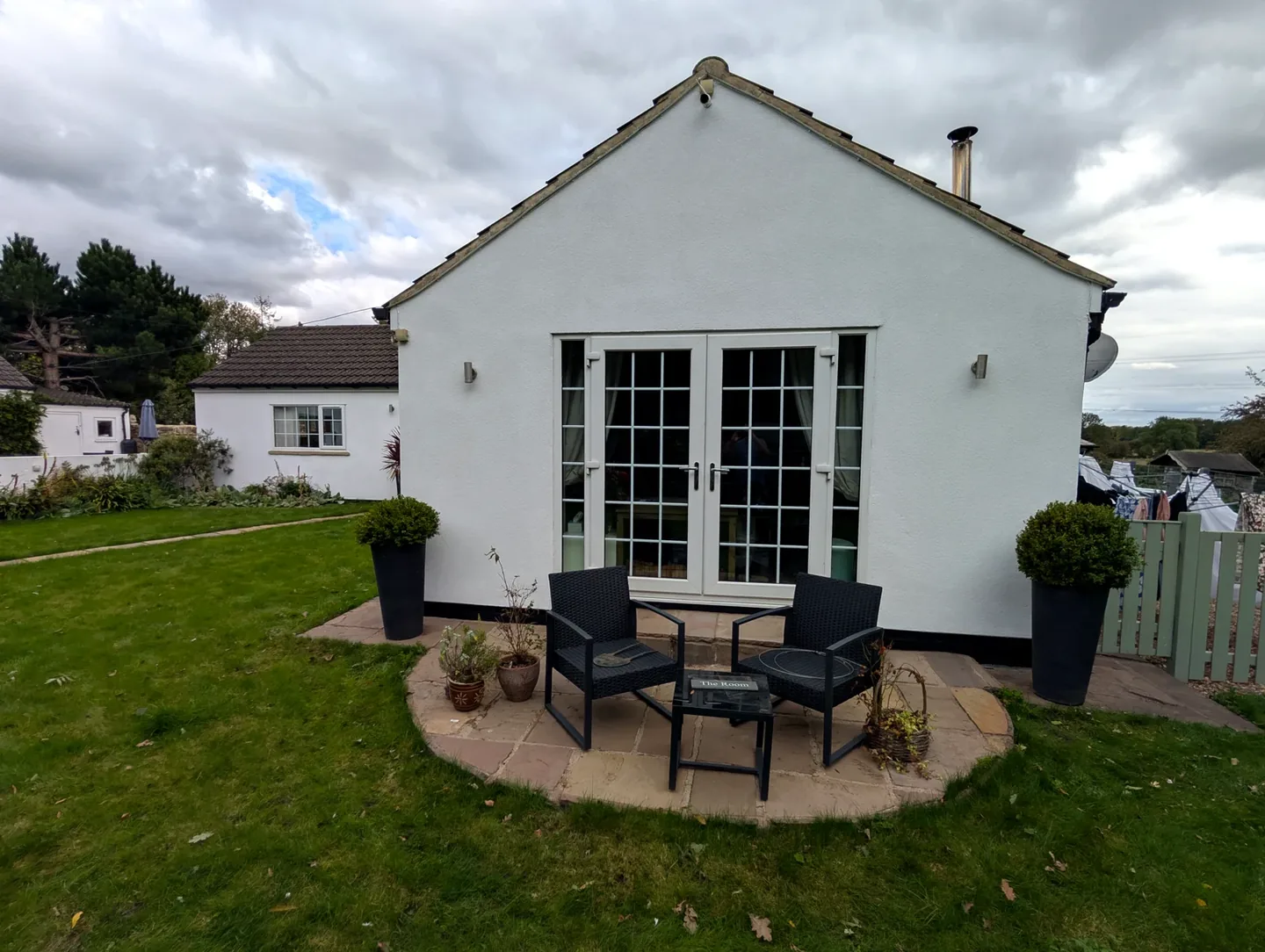 White painted single-storey home exterior with French doors opening onto a garden