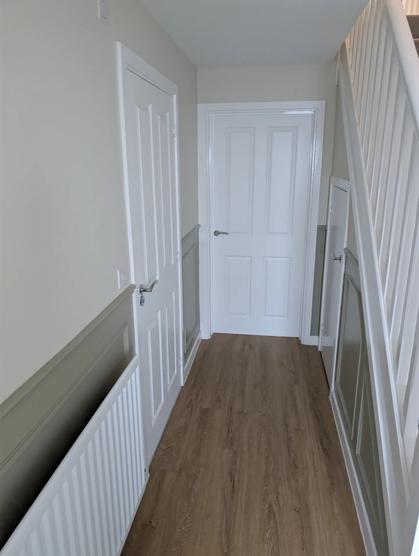 Neutral hallway with crisp white doors and painted wall mouldings