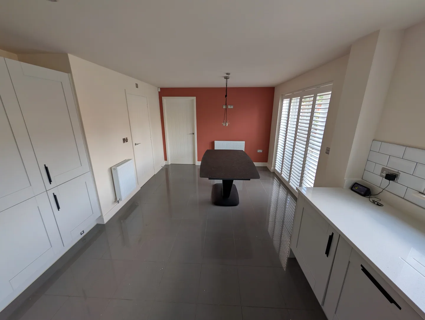 Kitchen dining space with terracotta accent wall and white joinery