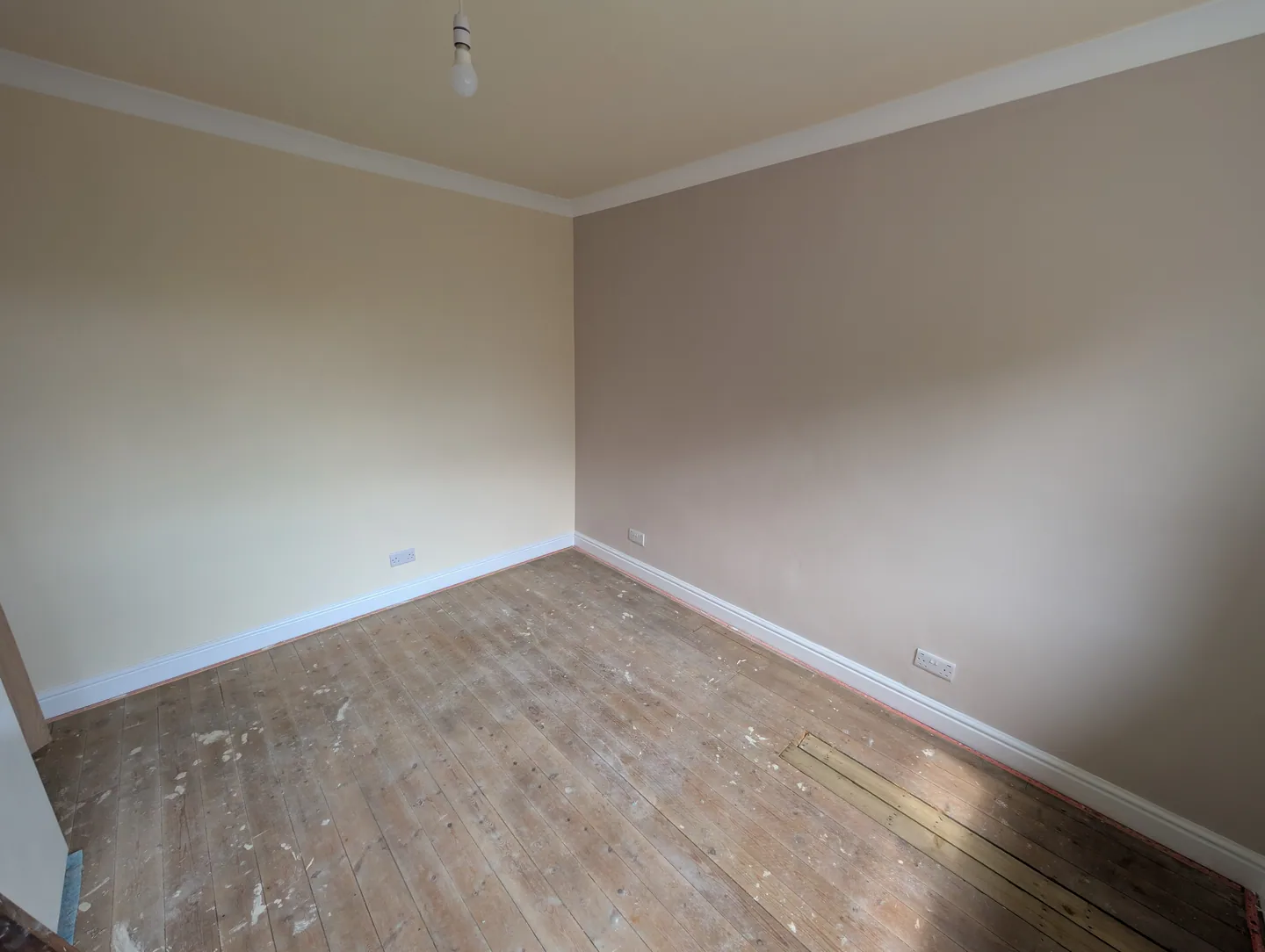 Empty room with softly coloured walls, white skirting and a wooden floor