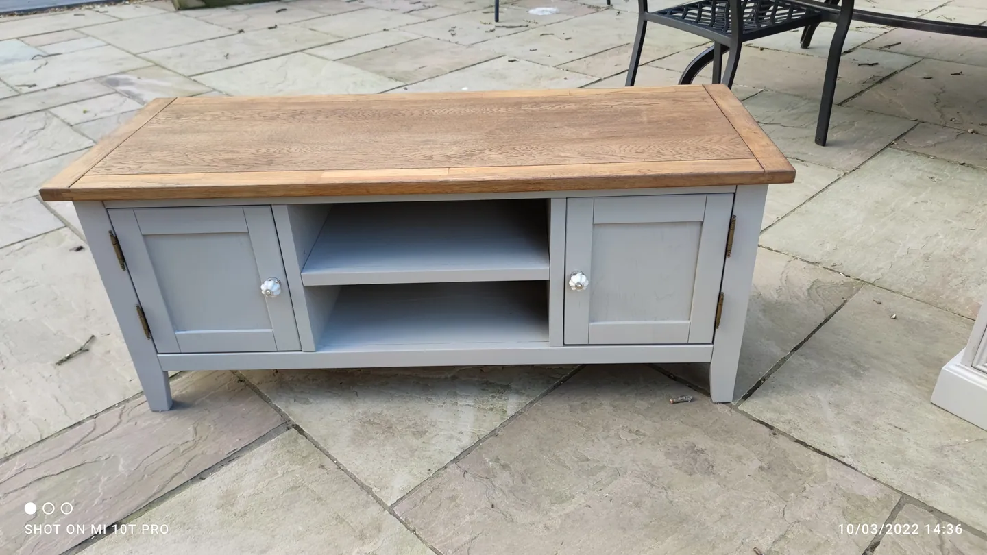 Pale grey painted television cabinet with a timber top