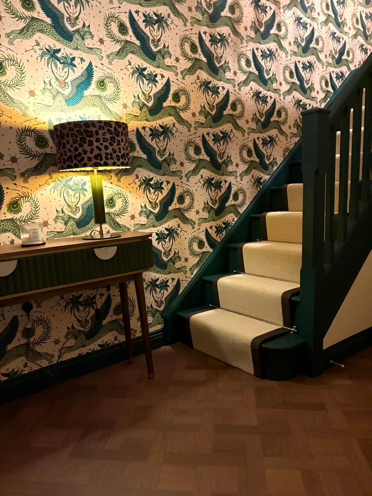 Patterned hallway wallpaper beside a dark green staircase