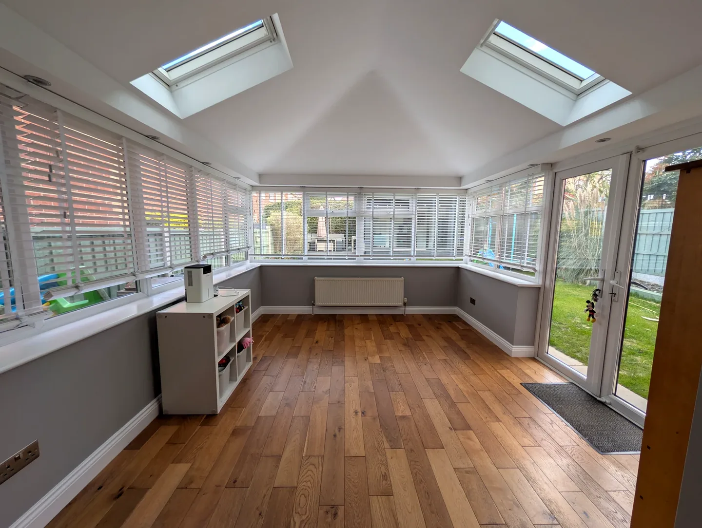Sunroom with wooden floor, pale grey walls and white window frames