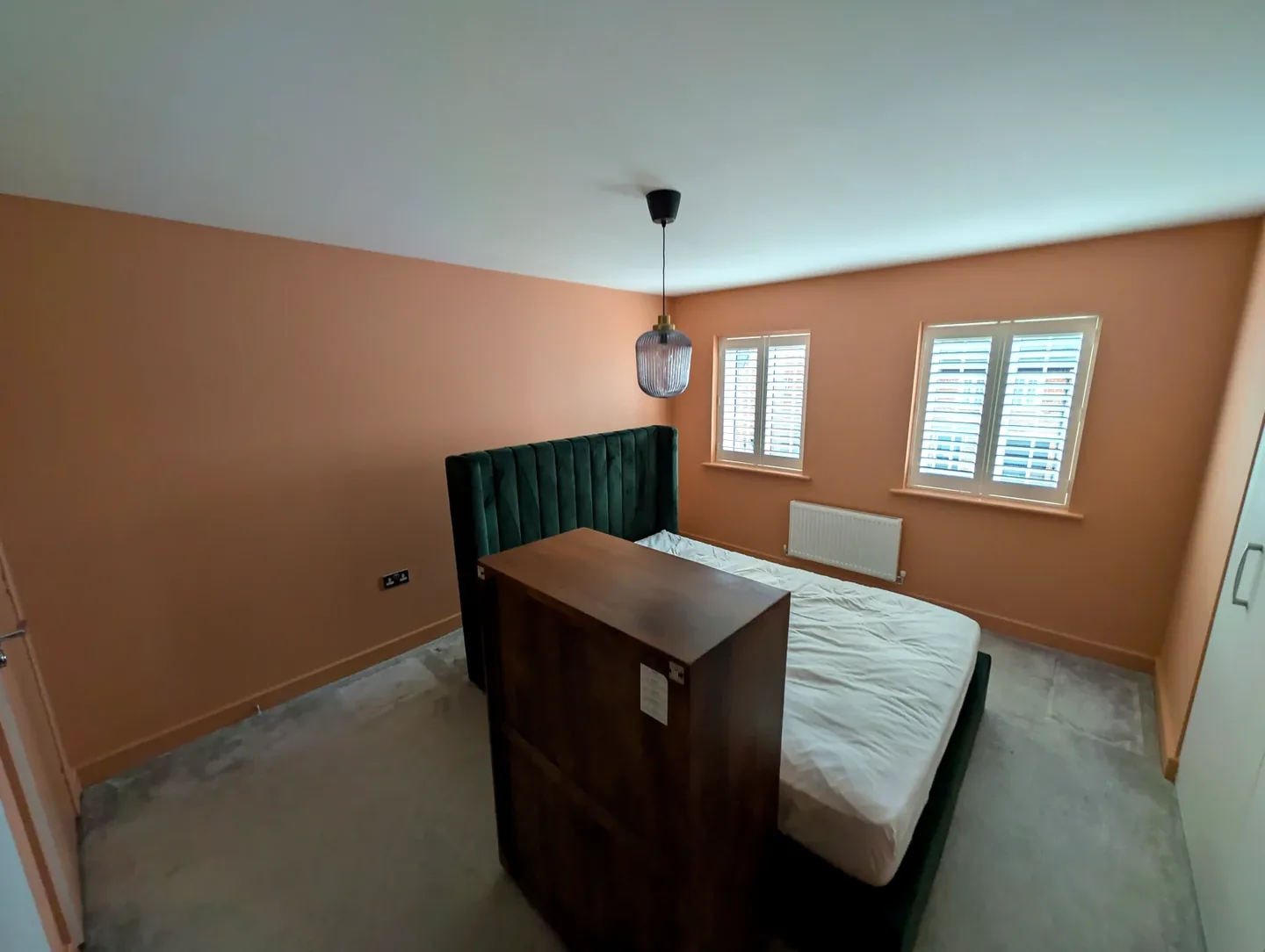 Terracotta bedroom walls with a green headboard and white shutters